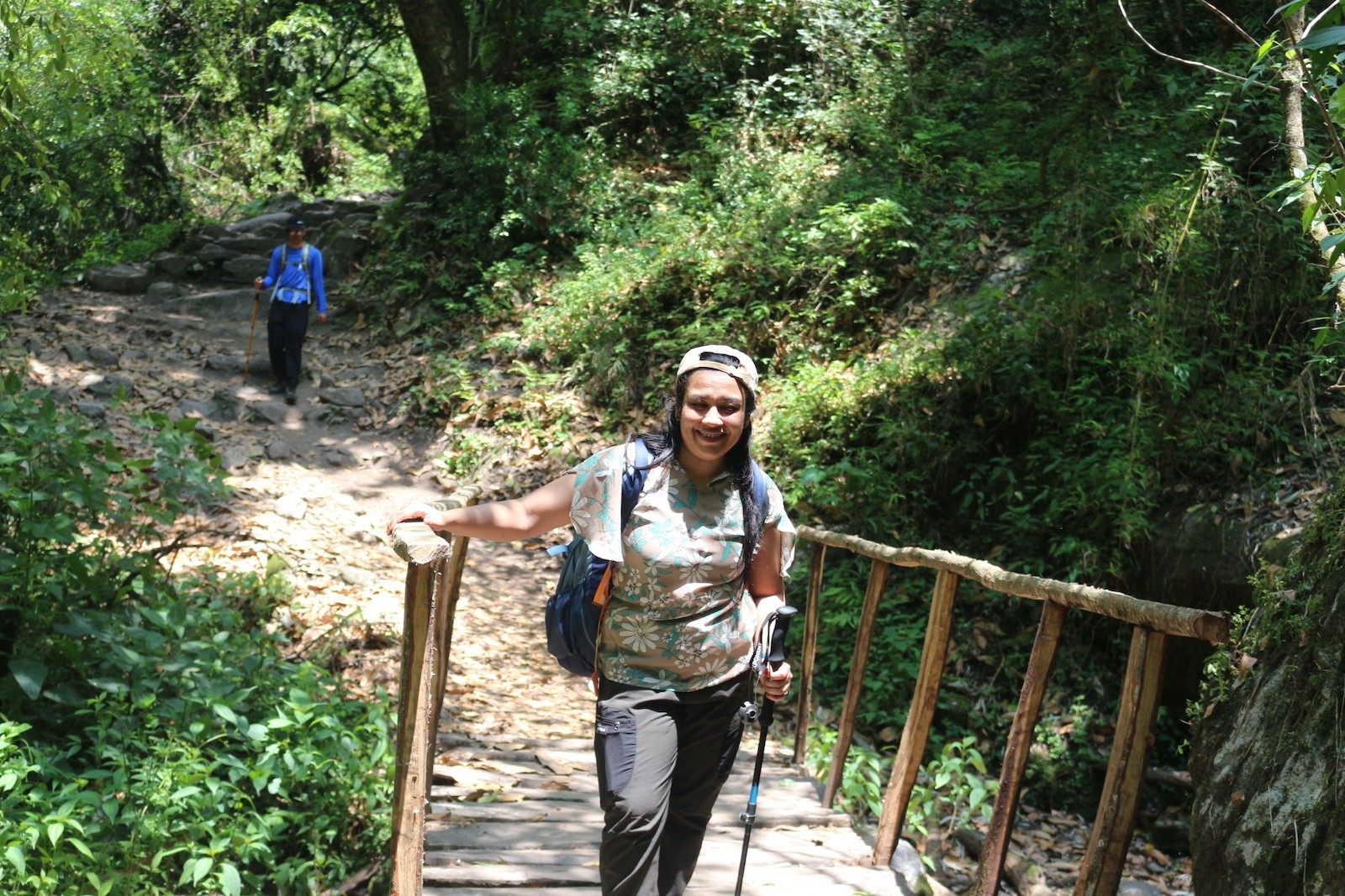 Trekkers walking along a well-defined trail through the lower Langtang Valley surrounded by lush forests and mountain scenery