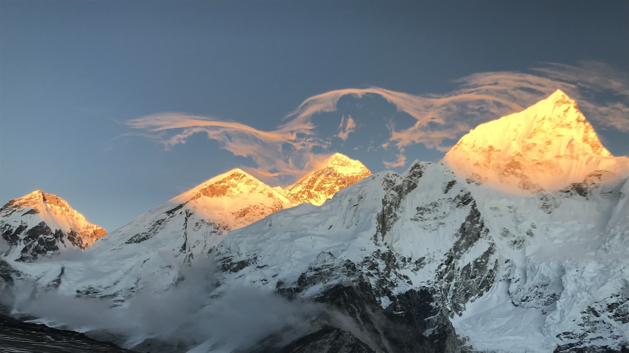 "Golden sunset over Mount Everest with glowing snow-covered peaks, dramatic Himalayan skyline, and warm evening light viewed from the Everest region in Nepal"