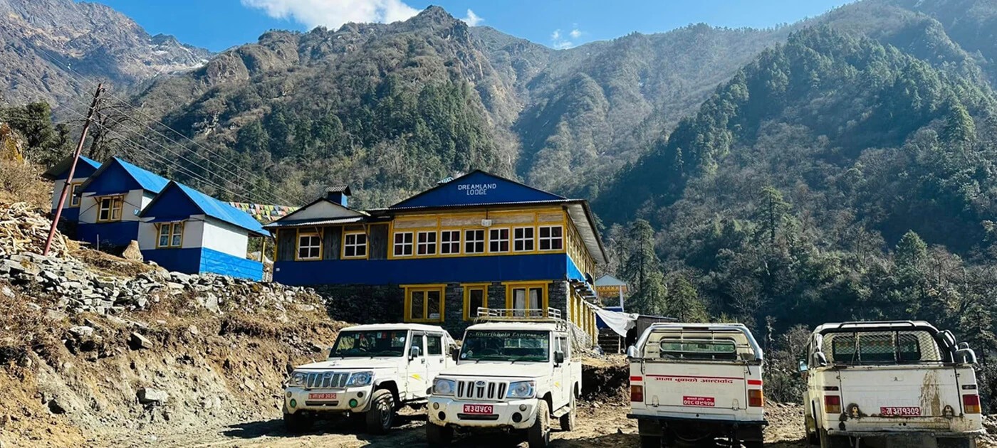 Jeeps parked outside a mountain lodge in Surke, the starting point of the overland Everest Base Camp Trek route, surrounded by forested hills and rugged Himalayan landscapes.