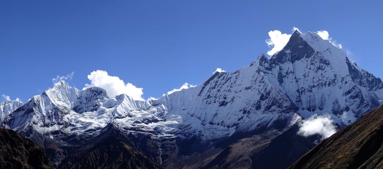 Snow-covered Annapurna mountain range under clear blue skies during the autumn trekking season.