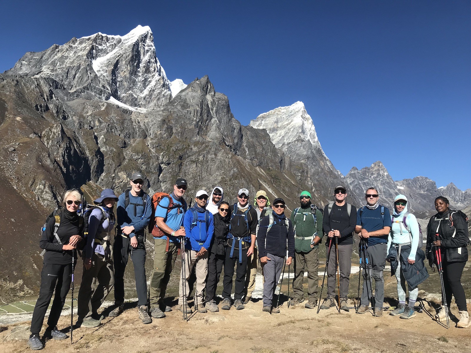 Group of trekkers wearing layered autumn trekking gear on the Everest Base Camp Trail in November, surrounded by the spectacular peaks of Ama Dablam, Kangtega, and the clear Himalayan sky.
