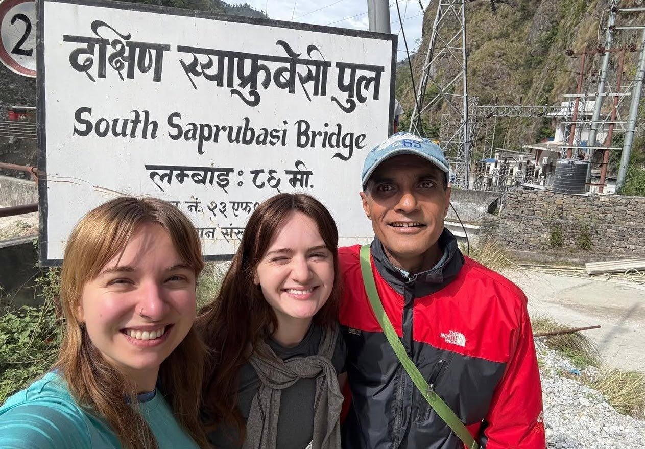 Trekkers beginning their Langtang Valley Trek from Syabrubesi, walking along the trail surrounded by green hills and Himalayan scenery in Nepal.