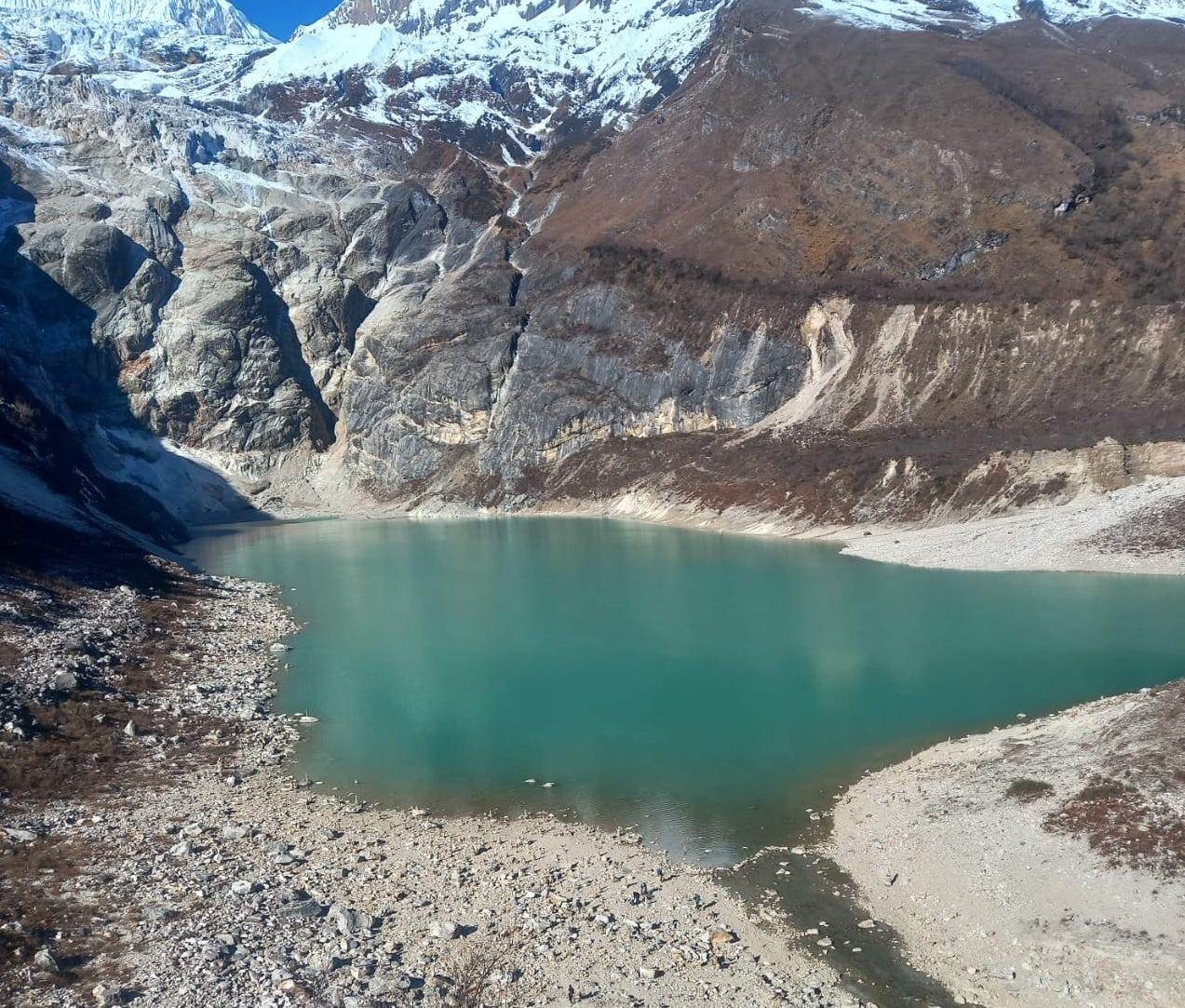 Turquoise waters of Birendra Lake surrounded by rugged moraines, alpine terrain, and spectacular views of Mount Manaslu in the Himalayas of Nepal.