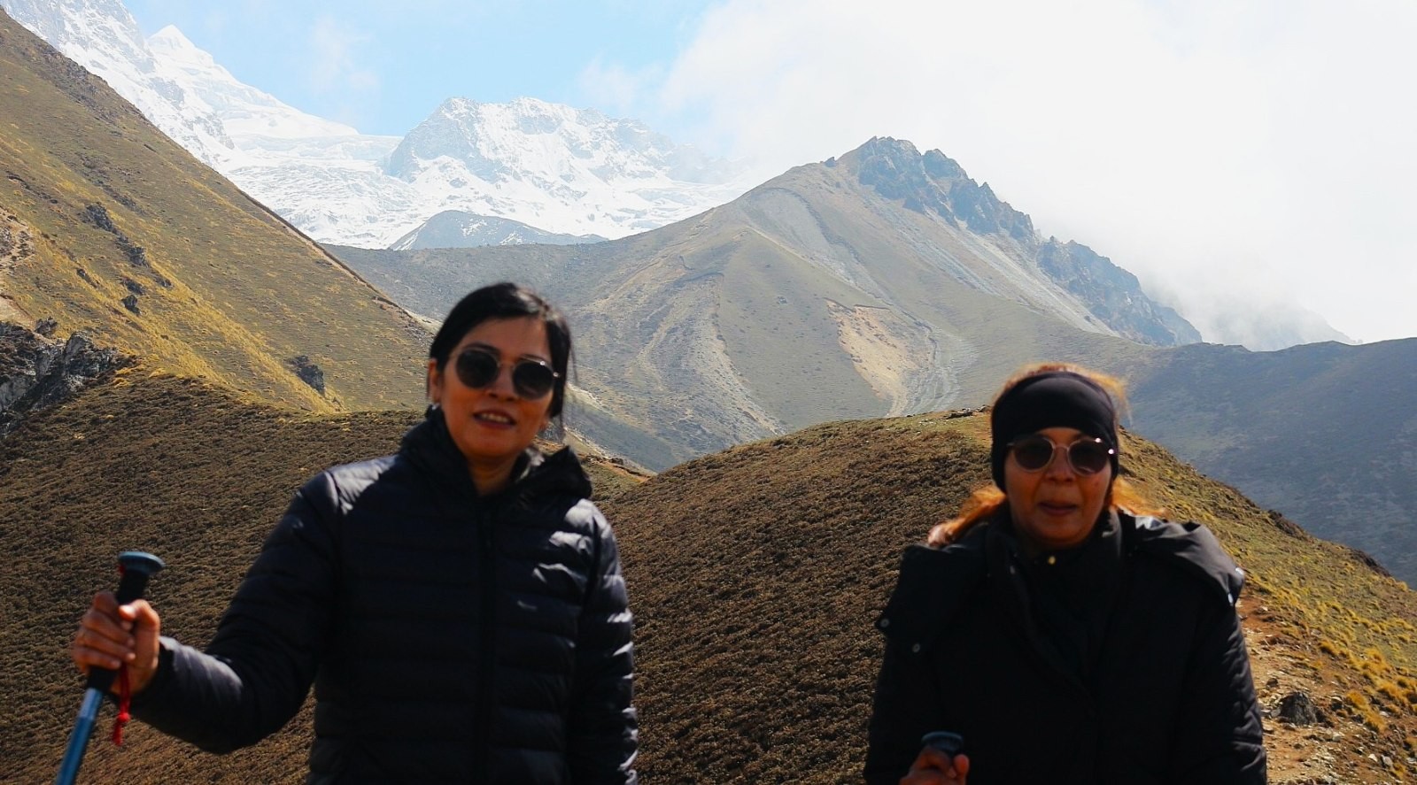 Well-equipped trekker wearing warm layers, a down jacket, gloves, and a hat in the cold high-altitude environment of the Langtang Valley Trek, Nepal