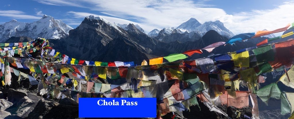 Colorful prayer flags fluttering at Cho La Pass with panoramic views of surrounding snow-capped Himalayan peaks under a clear autumn sky.