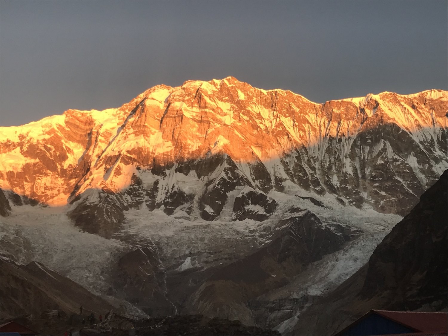 Golden sunrise illuminating Annapurna I with glowing snow-covered Himalayan peaks under a clear morning sky in the Annapurna Sanctuary, Nepal.