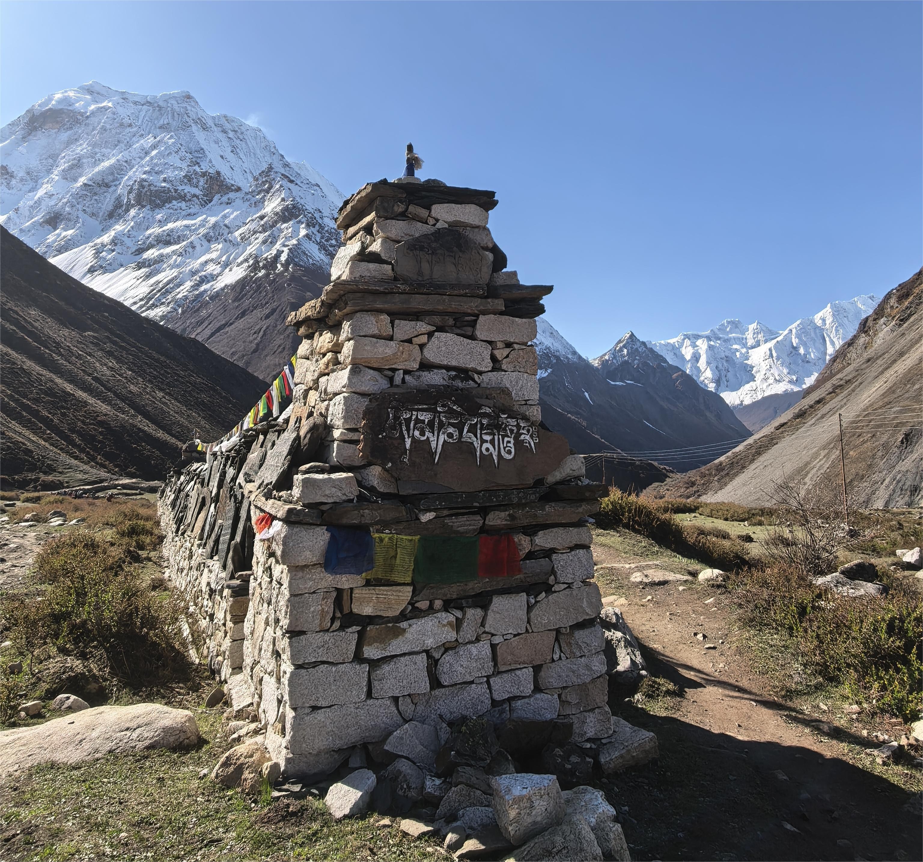 Traditional mani wall in Nepal Himalayas along Manaslu Circuit trekking trail representing ancient Buddhist culture and monastery heritage