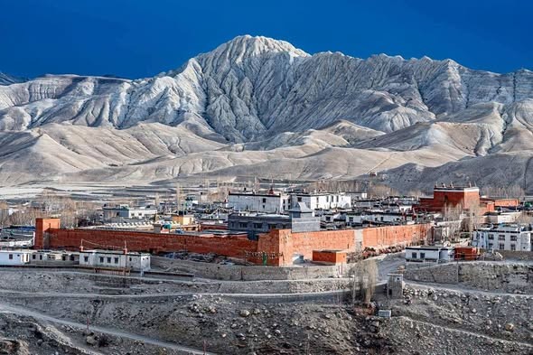 Rugged landscapes and traditional villages of Upper Mustang surrounded by dramatic barren mountains in northern Nepal.