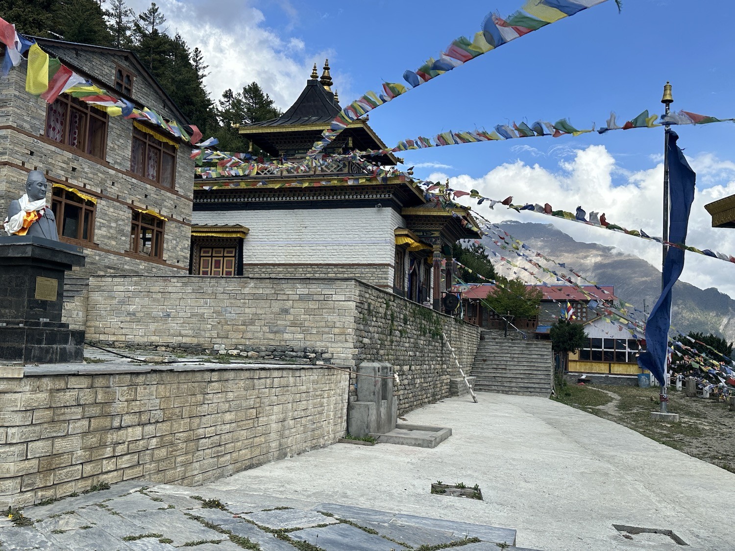 Ancient Pisang Monastery in Upper Pisang on the Annapurna Circuit Trek, featuring traditional Tibetan Buddhist architecture, colorful prayer flags, mani walls, and stunning views of Annapurna II and the surrounding Himalayan mountains.