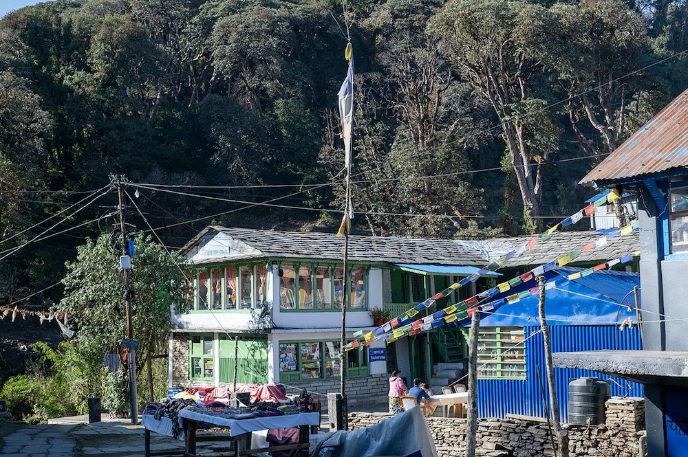 Teahouses and lodges open in Ghorepani on the Poon Hill Trek in September, with traditional buildings, prayer flags, and surrounding rhododendron forests.