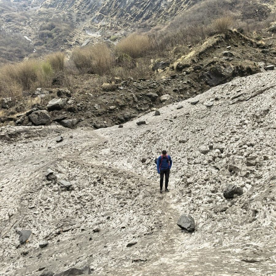 Avalanche descending steep snowy slopes in the Himalayan mountains, with fast-moving snow and debris flowing down a narrow valley in the Annapurna region.