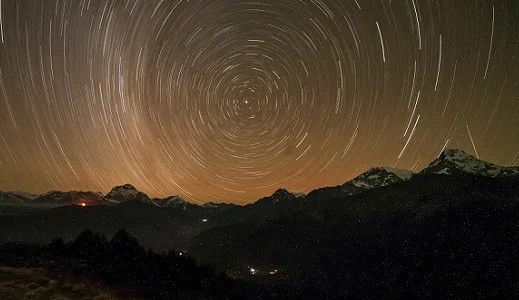 Star trails over the Himalayan sky from Poon Hill with mountain silhouettes at night.