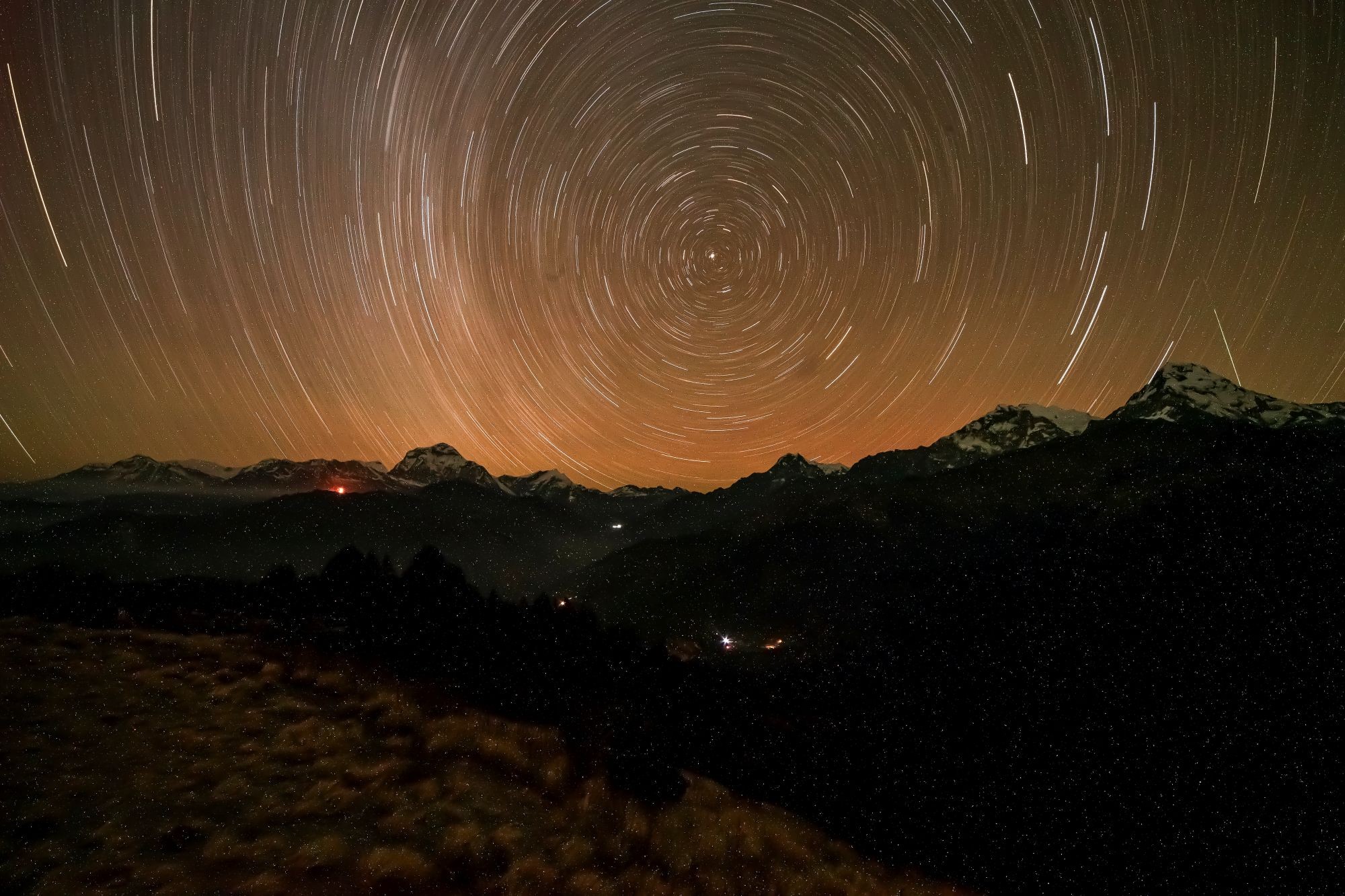 Star trails over the Himalayan sky from Poon Hill with mountain silhouettes at night.