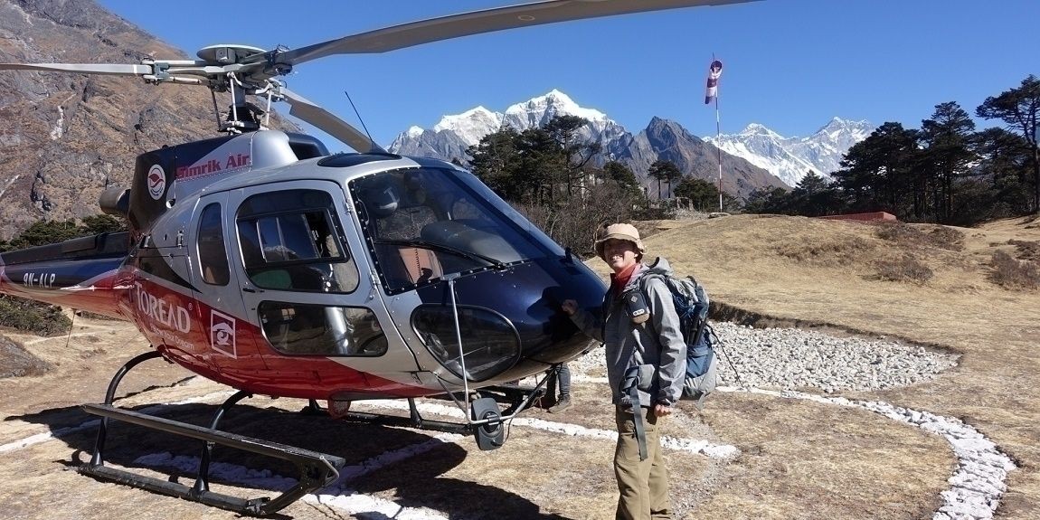 Tourists preparing to fly in helicopter with mountain backdrop