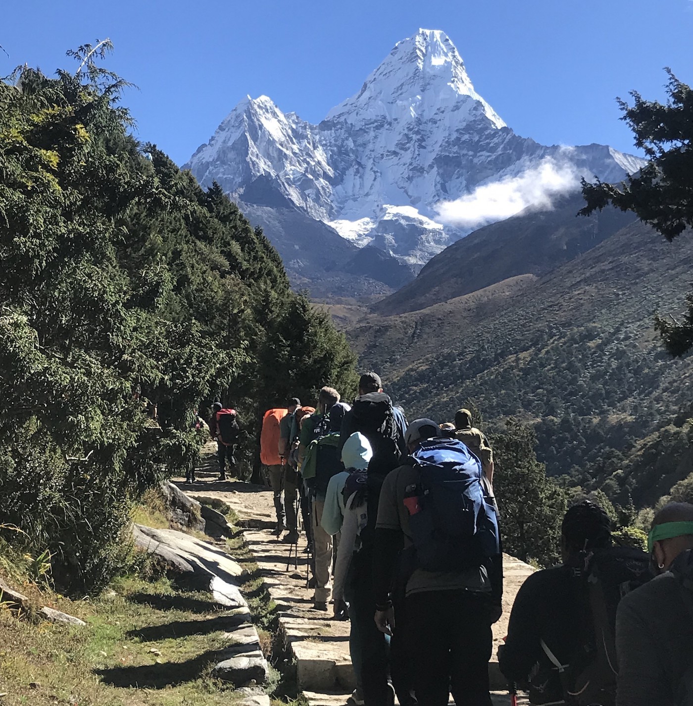 Trekker walking toward Pangboche on the Everest Base Camp Trail with the majestic Ama Dablam rising prominently in the foreground, surrounded by alpine valleys and rugged Himalayan landscapes. 