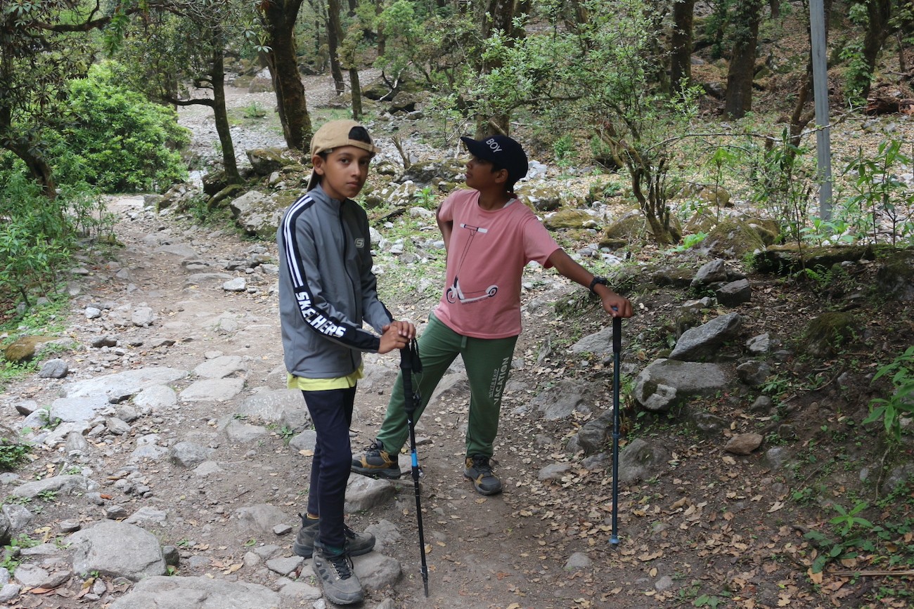 Beginner trekkers walking along the scenic Langtang Valley trail with Himalayan mountains in the background.