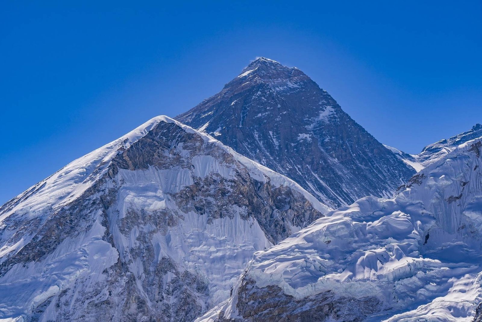 Majestic view of Mount Everest with its snow-covered summit rising above surrounding Himalayan peaks under a clear sky in Nepal.