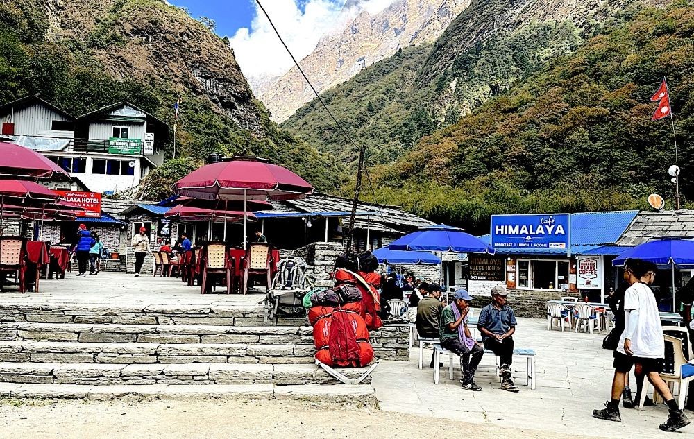 Crowded teahouse area with trekkers, porters, and backpacks during the Annapurna Base Camp autumn trekking season.