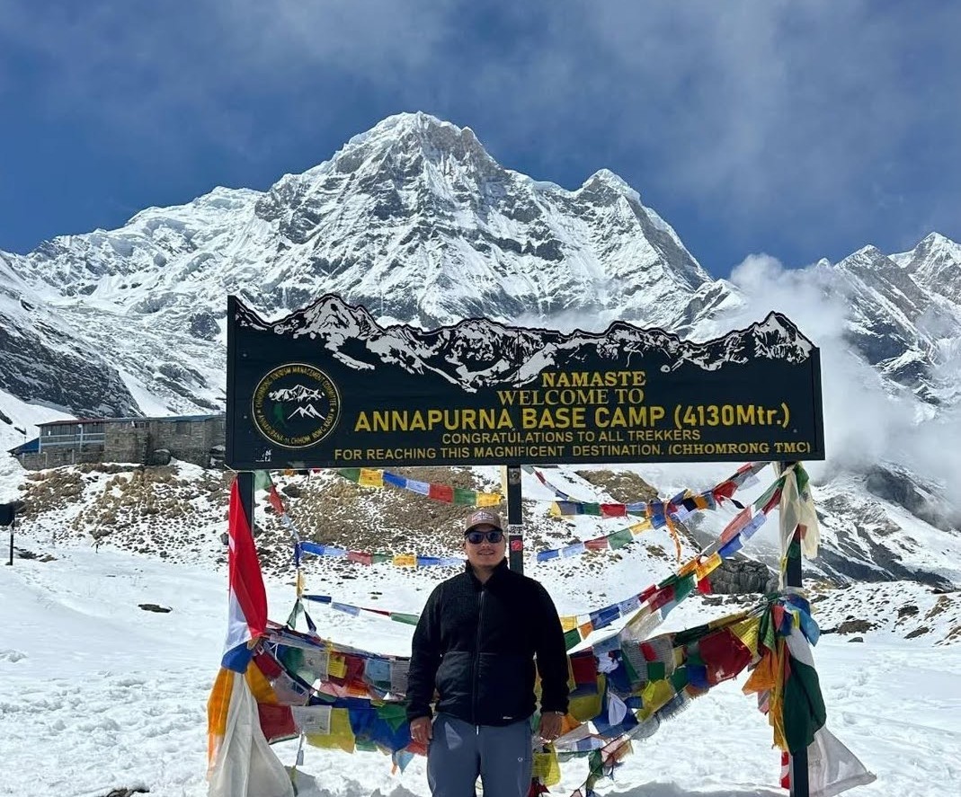 Annapurna Base Camp signboard with snow-covered Himalayan peaks in the background at 4,130 meters in Nepal.