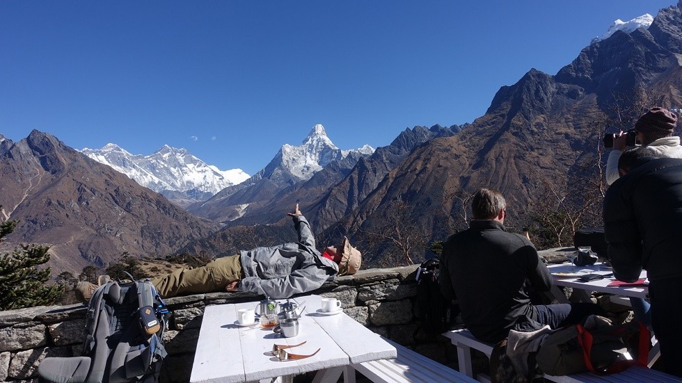 Outdoor restaurant terrace at Everest View Hotel with guests enjoying refreshments while overlooking Mount Everest, Ama Dablam, and the surrounding Himalayan peaks under a clear mountain sky.