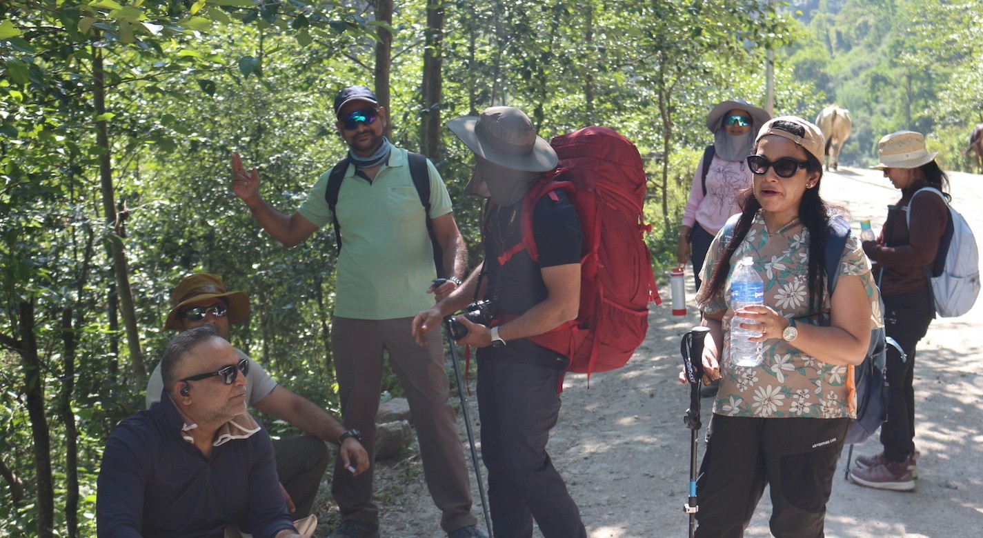 Trekkers walking through the beautiful Langtang Valley surrounded by snow-capped Himalayan peaks, forests, and traditional mountain villages in Nepal.