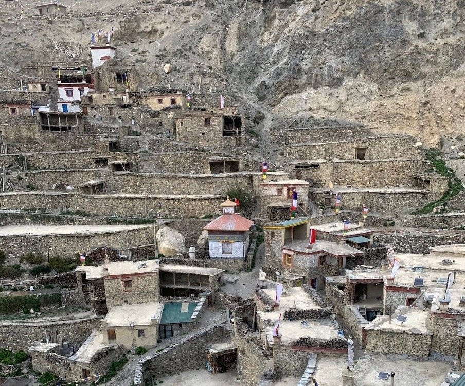 Trekkers walking through Nar Phu Valley with dramatic Himalayan peaks, rugged cliffs, and traditional mountain villages.
