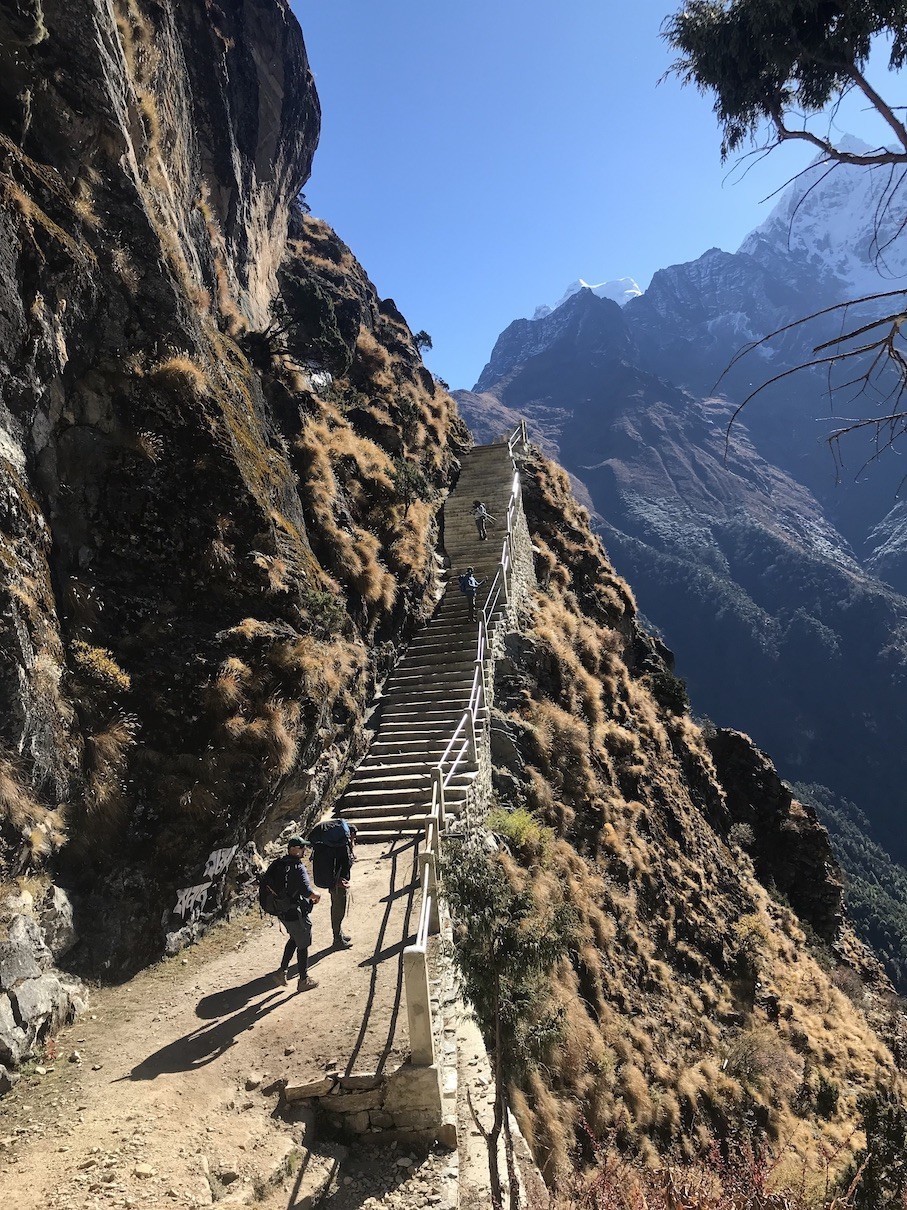 stone steps along the Everest Base Camp Trek winding through lush forests and traditional Sherpa villages, with spectacular Himalayan mountain views.