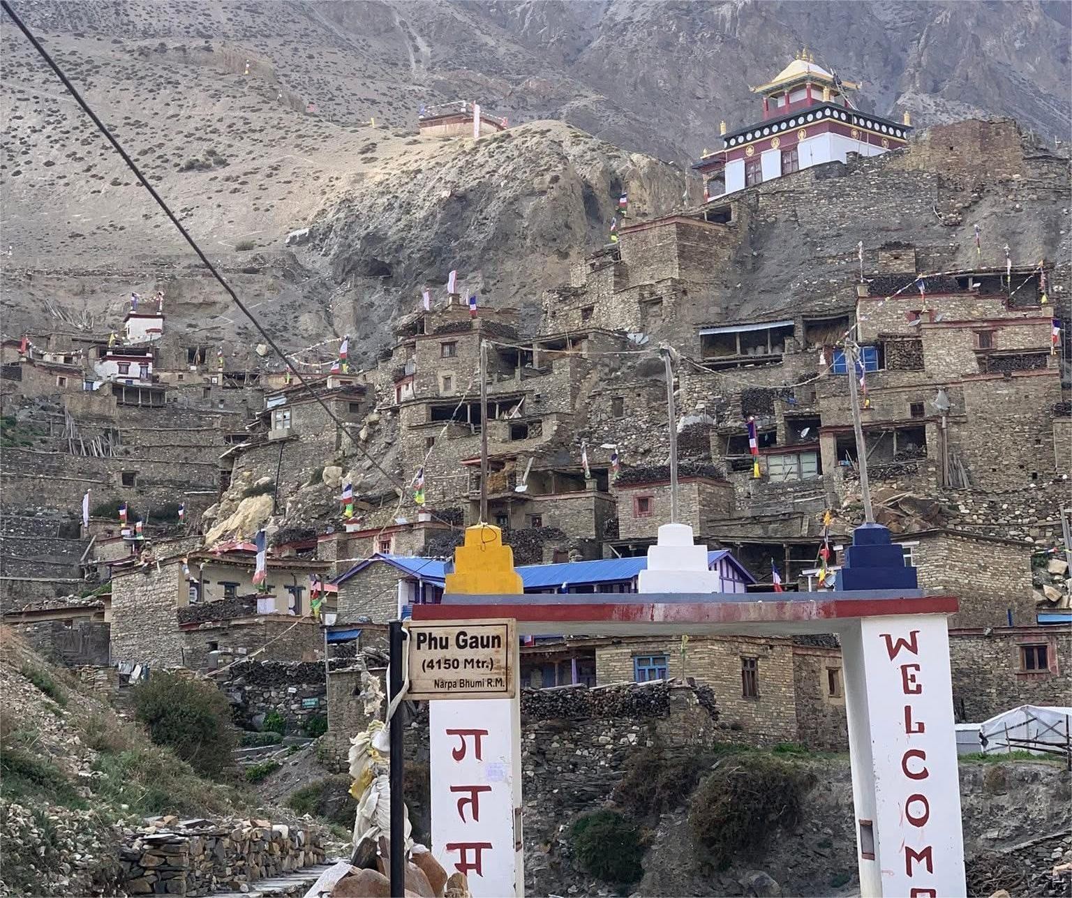 Ancient stone houses, Buddhist monastery, and the welcome gate of Phu Village (4,150 m) in the remote Nar Phu Valley Trek, Nepal.
