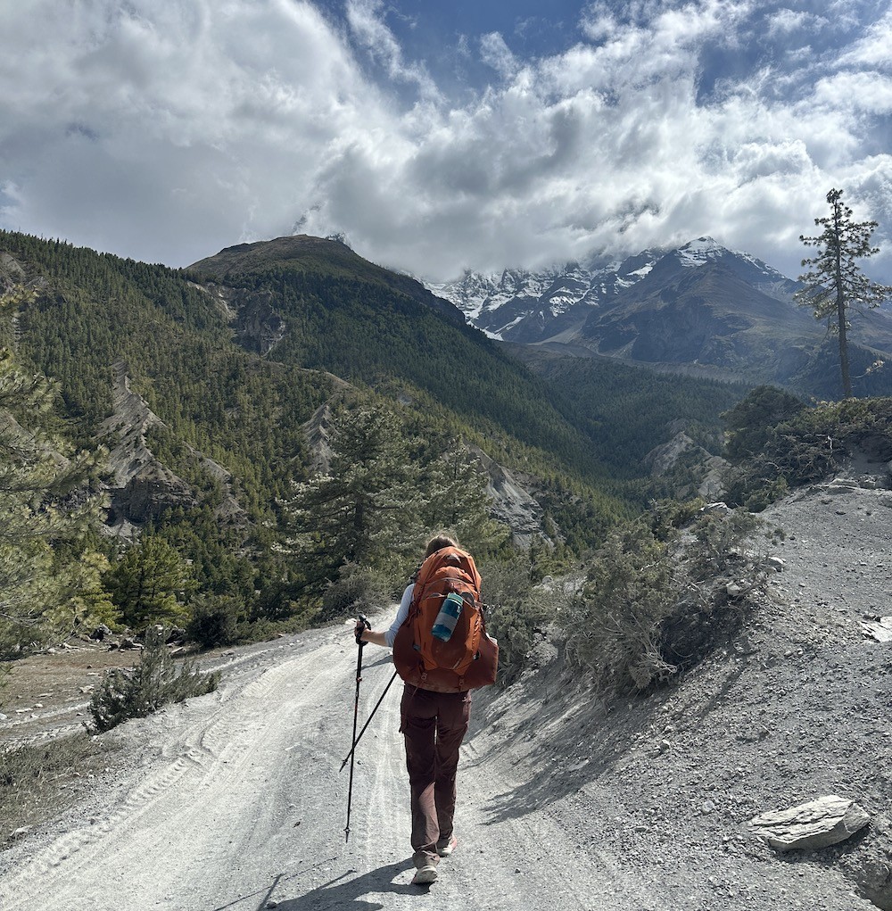 Solo female trekking in Nepal with Himalayan mountain views and backpack.