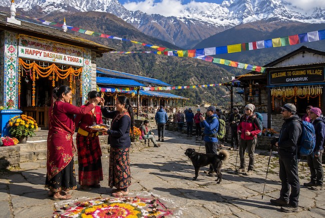 Dashain and Tihar celebrations in a Himalayan village with trekkers, prayer flags, and snow-capped mountains