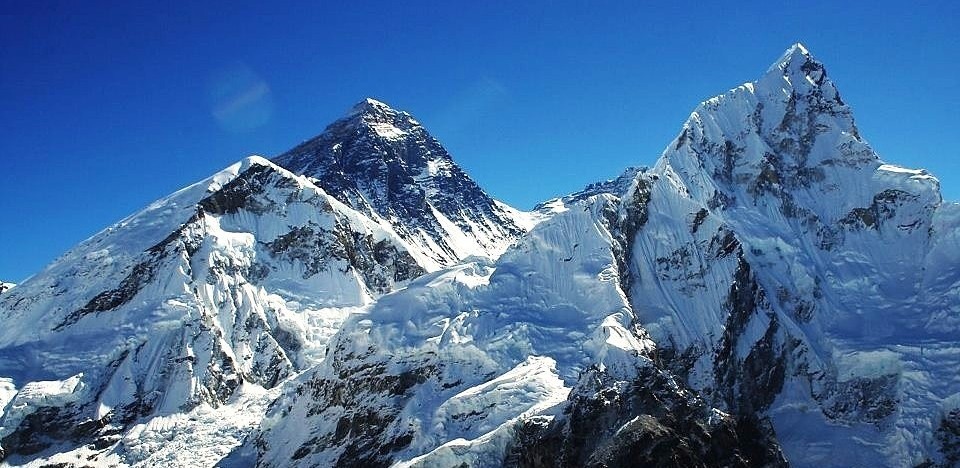Stunning view from Kala Patthar with Mount Everest, Nuptse, and snow-covered Himalayan peaks beneath crystal-clear blue skies.