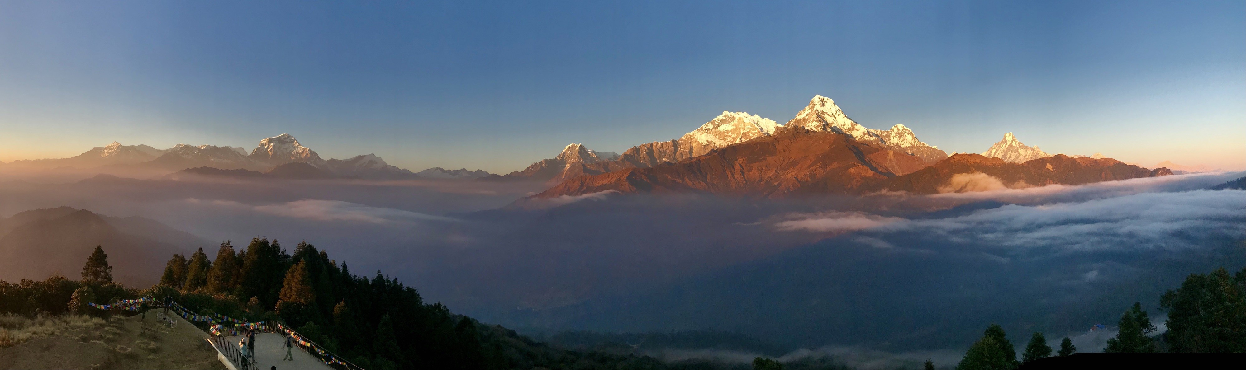 "Monsoon season at Poon Hill featuring lush green hills, mist-filled valleys, dramatic clouds, and panoramic views of the Annapurna and Dhaulagiri mountain ranges in Nepal."