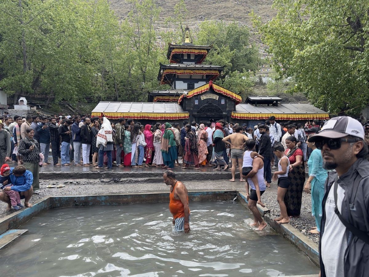 Pilgrims praying and walking around the sacred Muktinath Temple, with colorful prayer flags, ancient shrines, and snow-capped Himalayan peaks in the Mustang region of Nepal.
