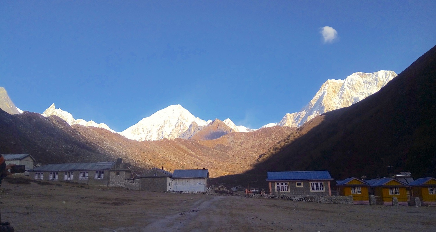 Scenic view of Bhimtang with alpine valley landscape, snow-capped Himalayan peaks, and trekking trail descending through forested hills in Nepal.
