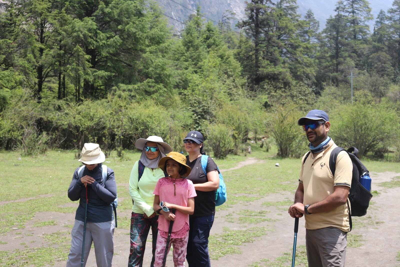 Trekkers walking uphill on a rugged Langtang Valley trail surrounded by steep mountain slopes and Himalayan peaks.