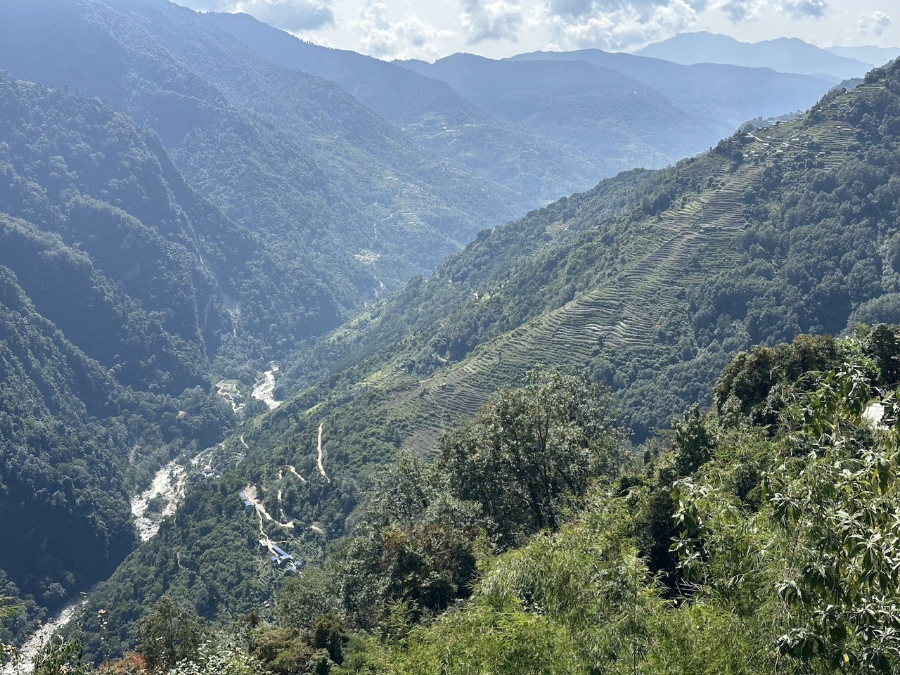 Scenic view on the way to Jhinu Danda featuring deep river valleys, terraced hillsides, traditional mountain villages, lush forests, and beautiful Annapurna foothill landscapes.
