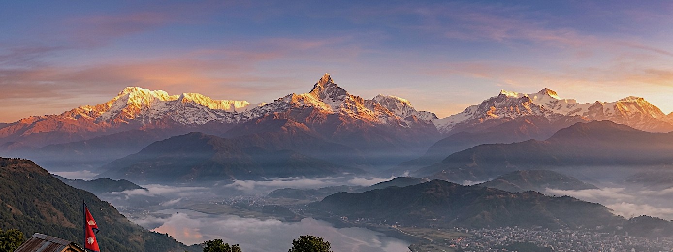 Panoramic sunrise view from Sarangkot overlooking Pokhara Valley, with Machhapuchhre (Fishtail), Annapurna, Dhaulagiri, and surrounding Himalayan peaks glowing in golden morning light above mist-covered hills.