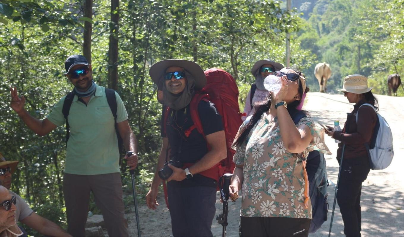 Trekkers hiking through Langtang Valley, following scenic mountain trails surrounded by forests, rivers, traditional villages, and spectacular snow-capped Himalayan peaks.