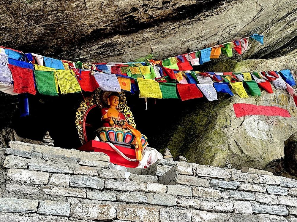 Hinku Cave along the Annapurna Base Camp trekking route, showing a rocky overhang and narrow passage surrounded by steep cliffs and forested Himalayan terrain. 
