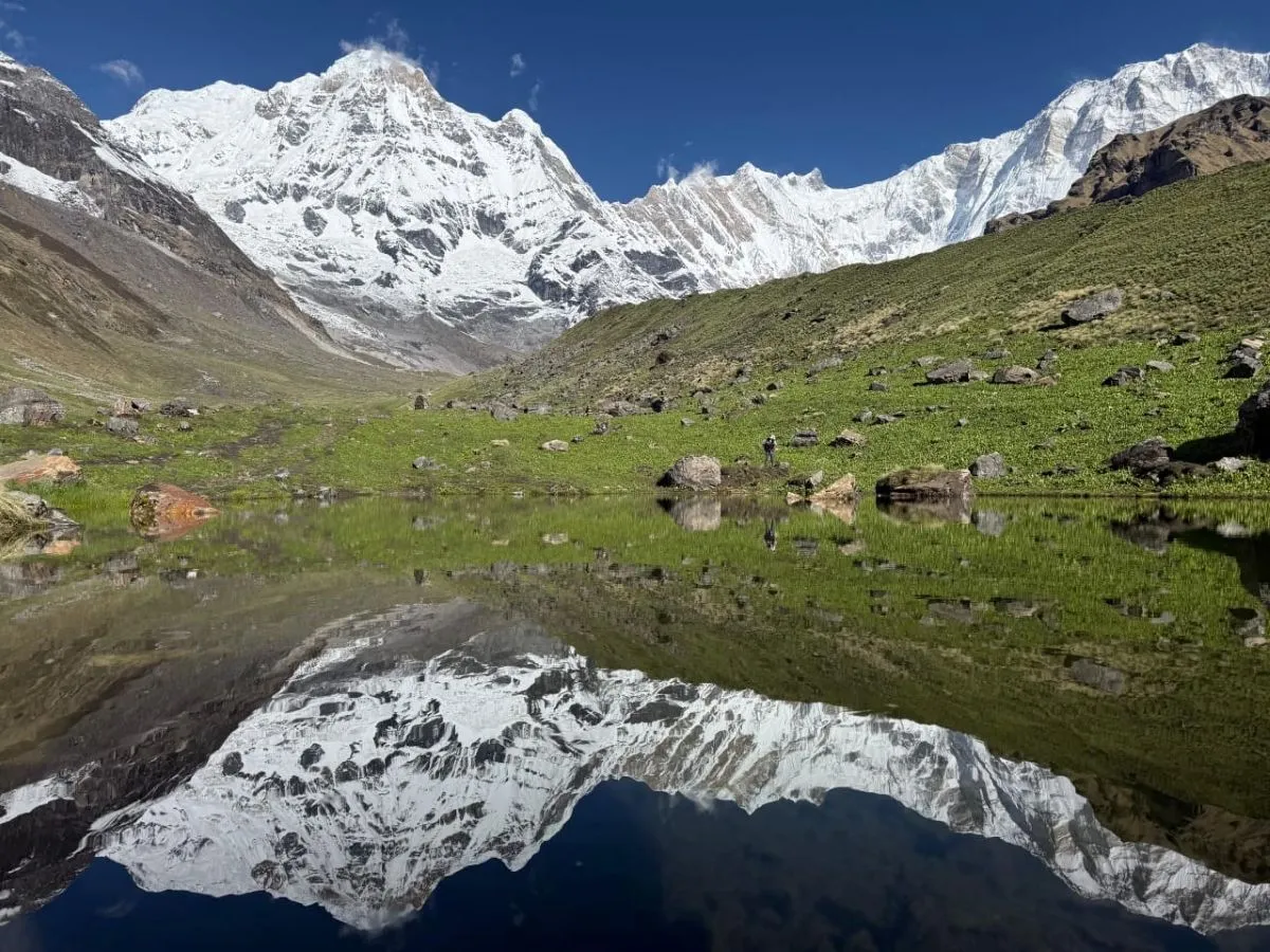 Annapurna Sanctuary in September with snow-capped peaks, green meadows, and mountain reflections in Nepal.