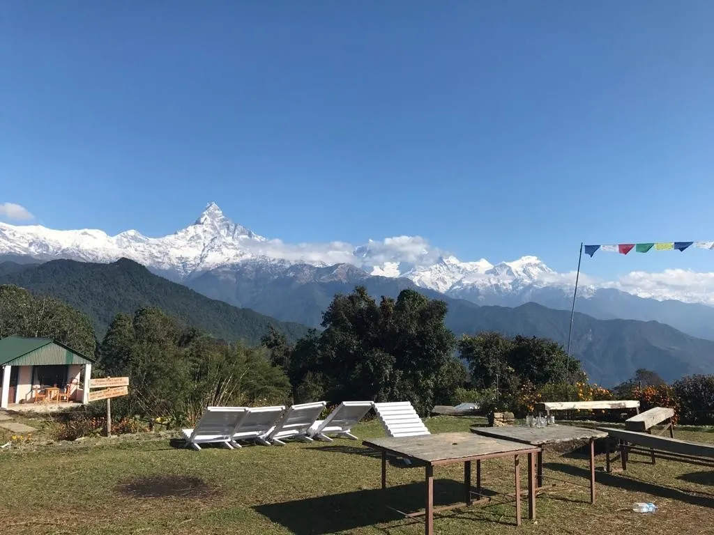 Scenic view of Australian Camp on the Mardi Himal Trek route, featuring traditional lodges, green hills, trekkers resting, and panoramic views of the Annapurna and Machhapuchhre mountain ranges.