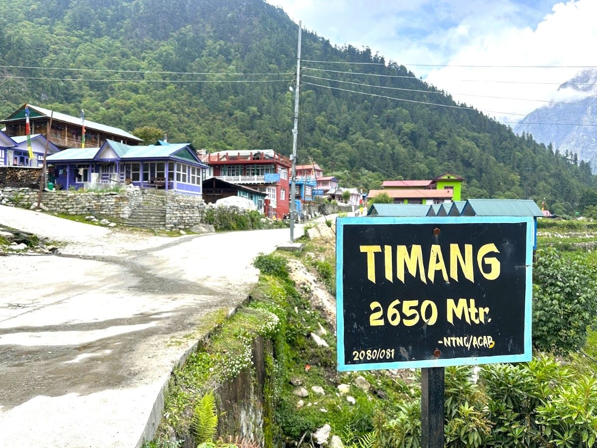 Timang Village on the Annapurna Circuit Trek with traditional stone houses, colorful prayer flags, lush pine forests, terraced hillsides, and spectacular views of Manaslu and Lamjung Himal under clear Himalayan skies.