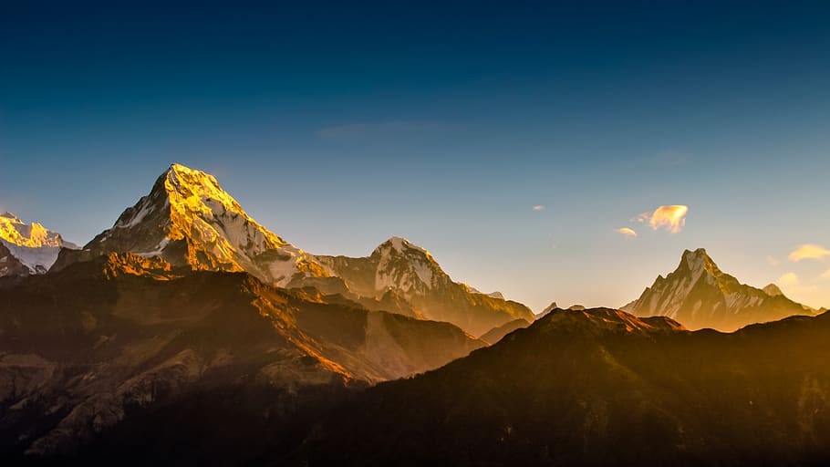 Sunlight shining over Himalayan mountains, illuminating snow-capped peaks with golden rays and clear skies in a scenic mountain landscape of Nepal.