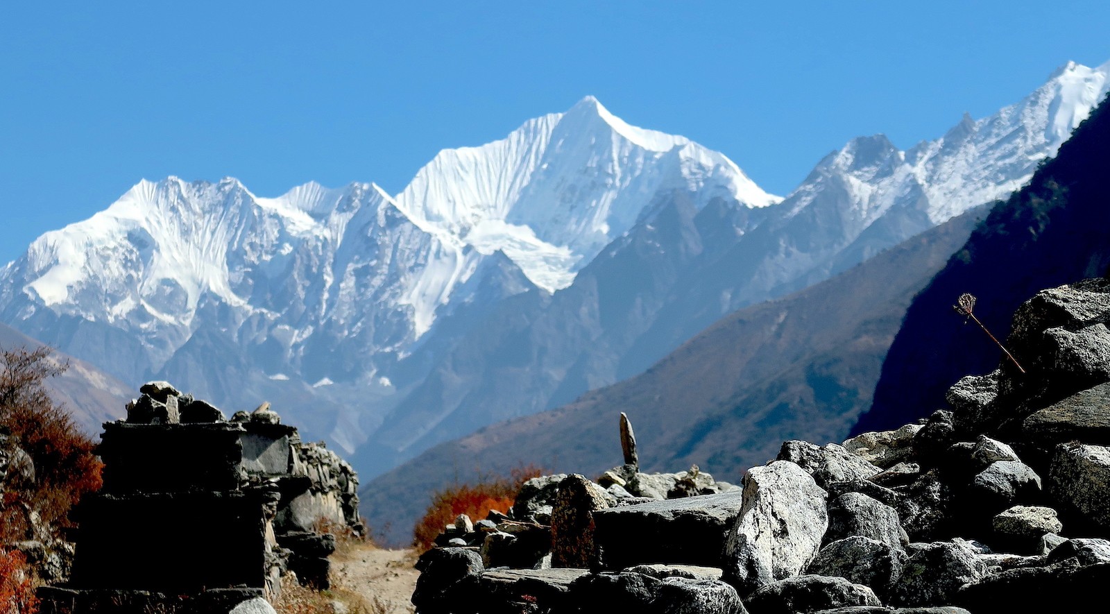 "Spectacular mountain view from Kyanjin Gompa in Langtang Valley, Nepal, featuring Langtang Lirung, snow-capped Himalayan peaks, glaciers, and clear blue skies during the trekking season." 