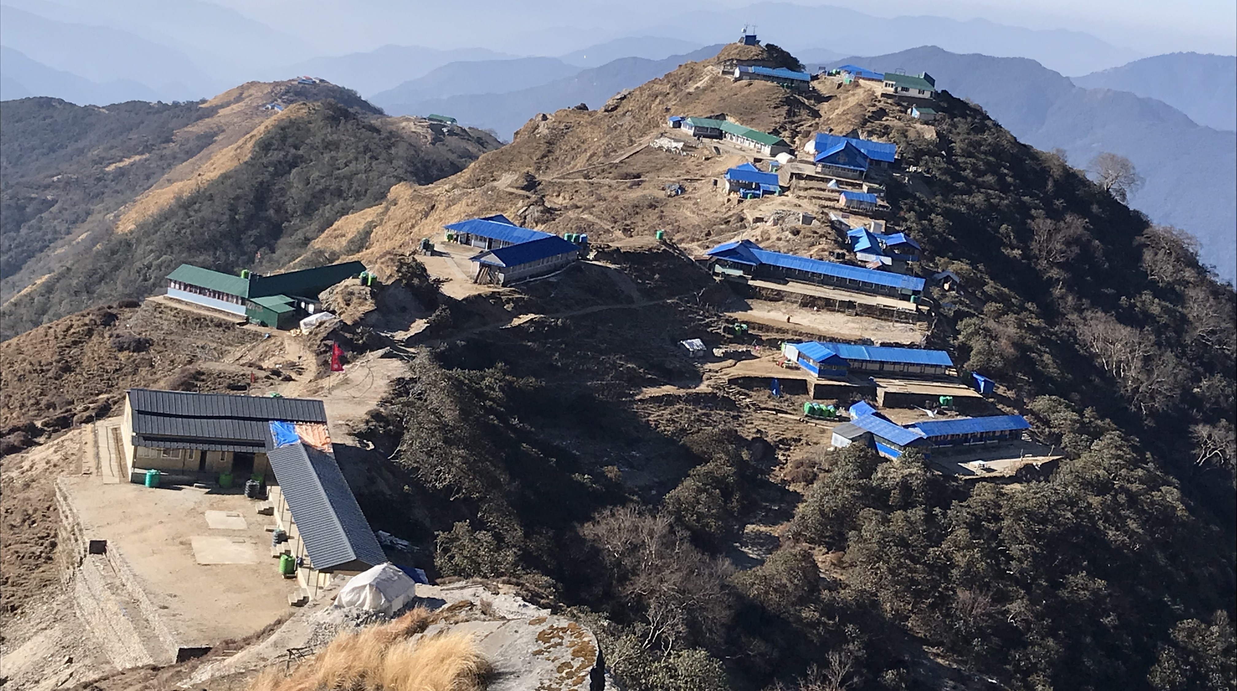 Mountain lodges at High Camp on the Mardi Himal Trek surrounded by snow-capped Himalayan peaks.