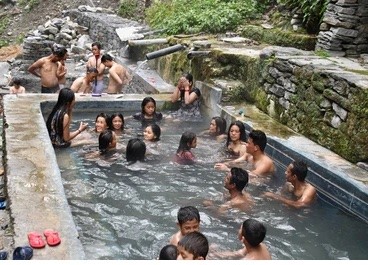 Jhinu Danda Hot Spring beside the Modi Khola River, featuring natural thermal pools surrounded by lush green forests and peaceful Himalayan scenery on the Annapurna Base Camp Trek.