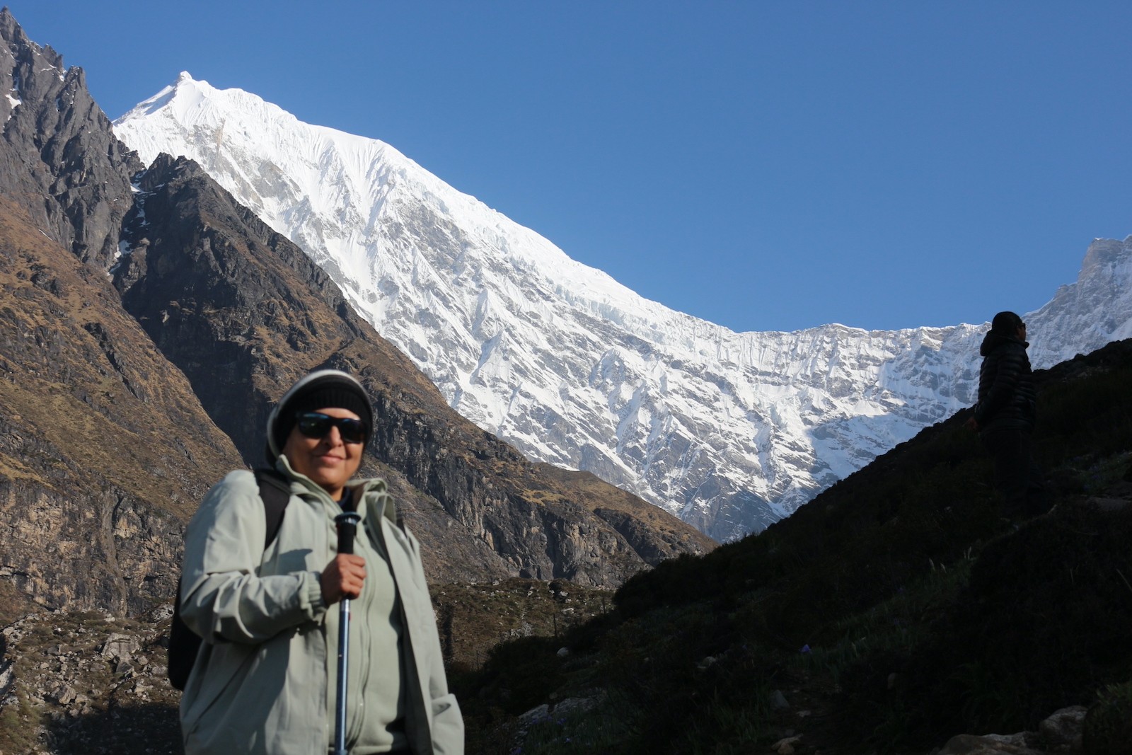 Trekker using heavy-duty trekking poles while crossing a rocky glacial moraine in the Langtang Himalayas of Nepal.