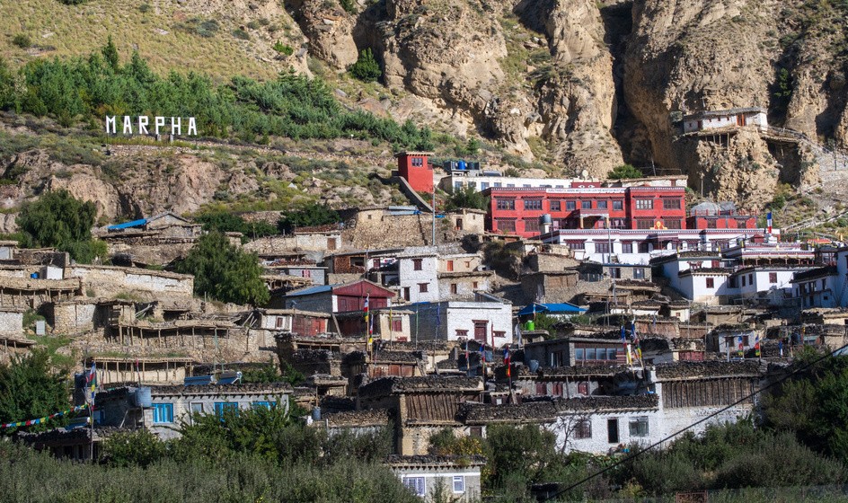 Marpha village in Mustang Nepal with traditional whitewashed houses, apple orchards, and Himalayan mountain backdrop”