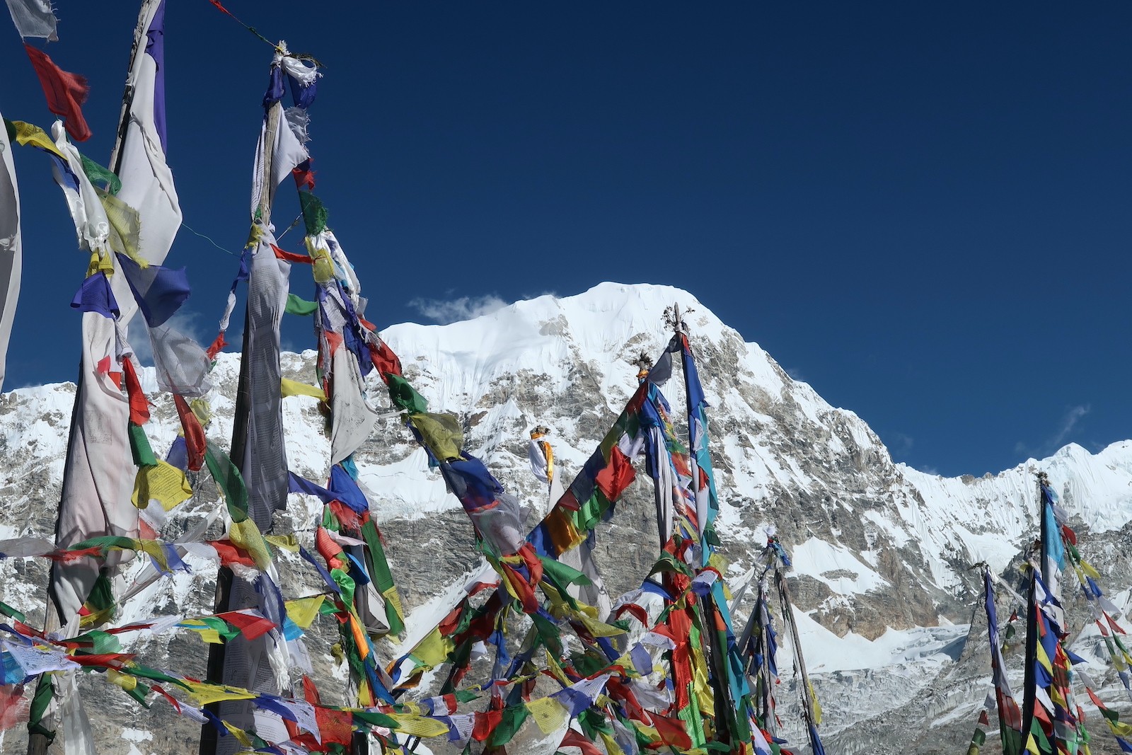 "Kyanjin Gompa in Langtang Valley during autumn with clear blue skies, colorful prayer flags, traditional lodges, and snow-capped Himalayan peaks, showcasing the best season to visit."  