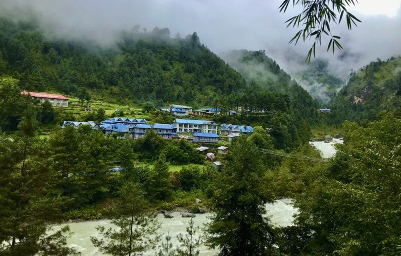 "Phakding village beside the Dudh Koshi River with suspension bridge, pine forest, and Himalayan scenery on the Everest Base Camp trekking trail"